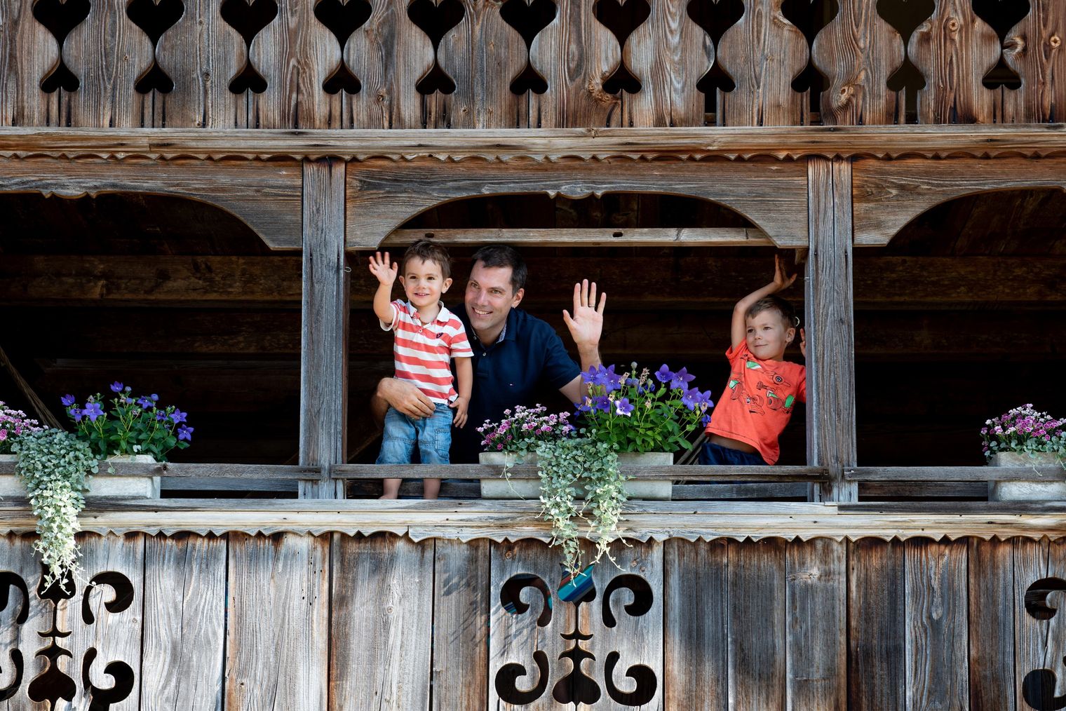 Vater mit zwei Kindern winkt vom Stöckli des Bauernhofs Obermörisegg